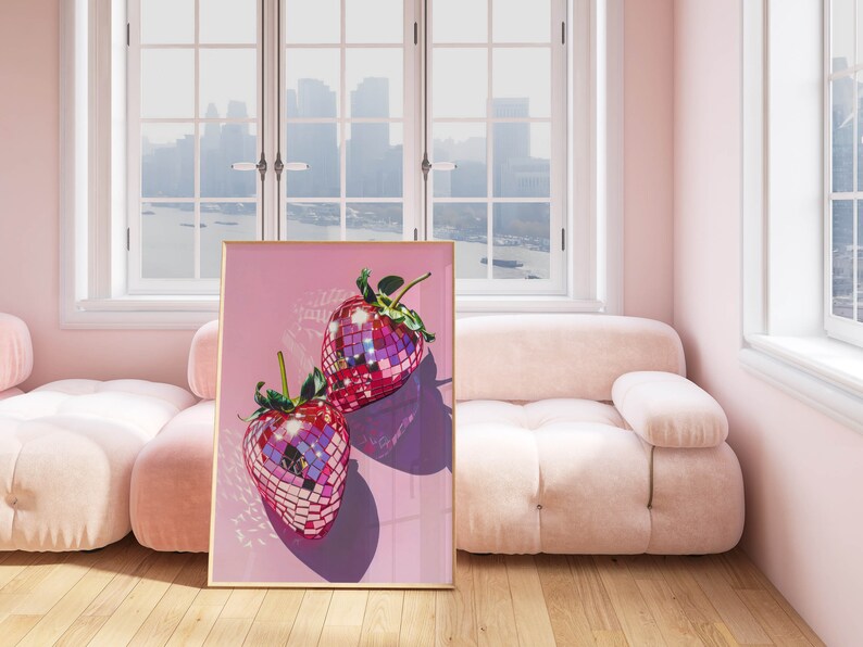 May include: A framed print of two pink disco ball strawberries on a pink background.