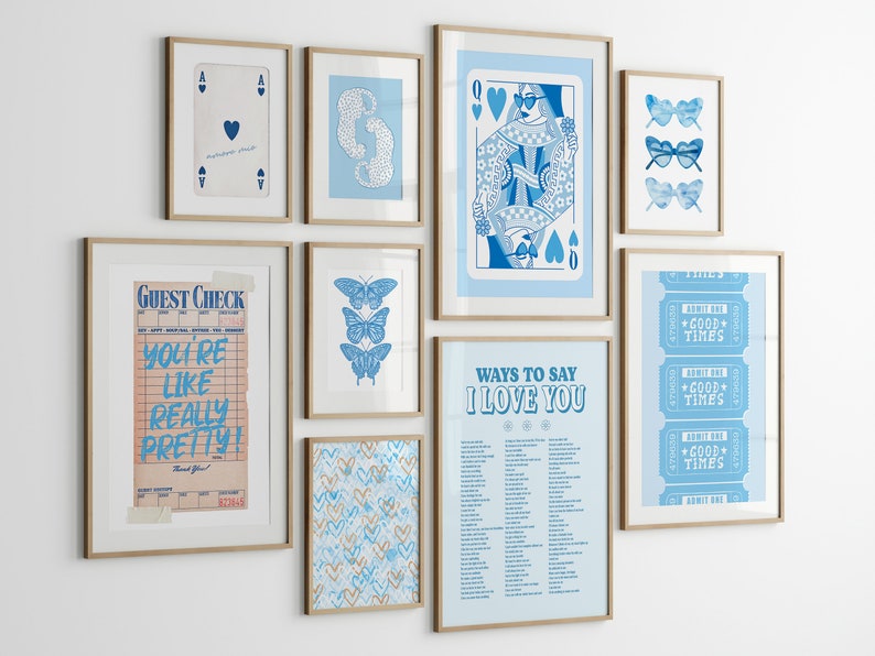 May include: A gallery wall with nine framed prints in a blue and white color scheme. The prints feature a playing card, butterflies, sunglasses, a ticket stub, a guest check, and a list of ways to say "I love you".