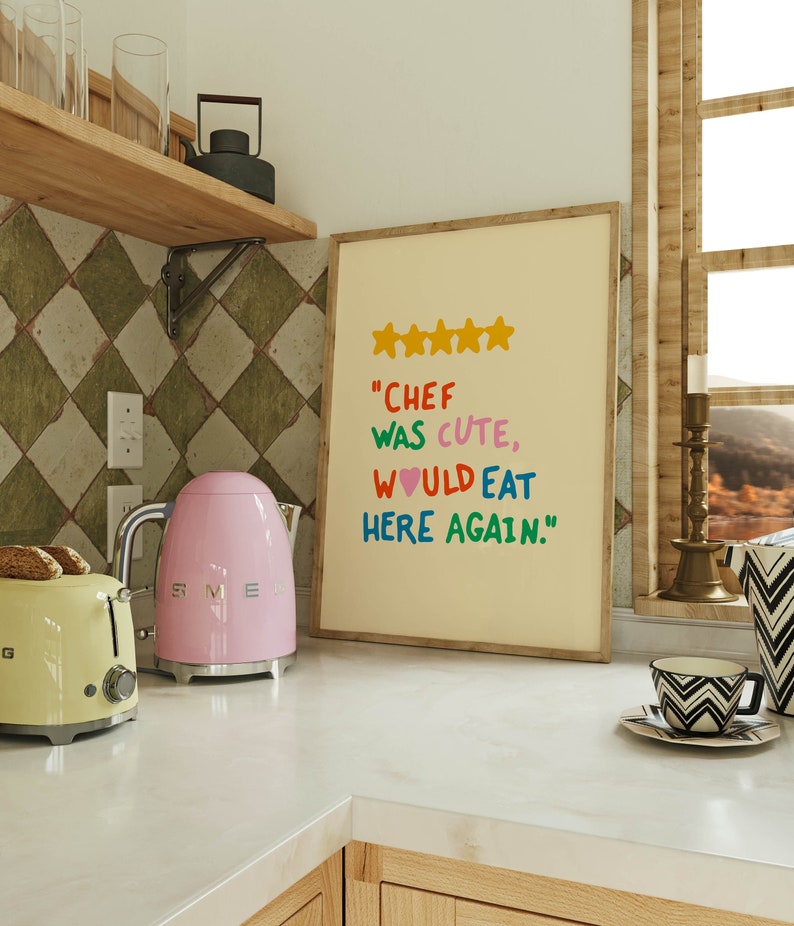 May include: A framed print with a yellow background and colorful text that reads "Chef was cute, would eat here again." with five yellow stars above the text.