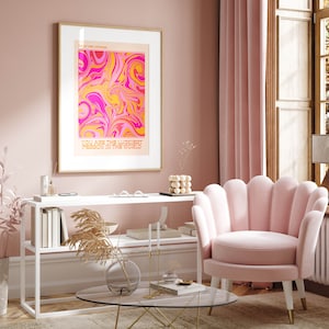 Peut inclure: Une impression abstraite en spirale rose et jaune avec le texte "You are the luckiest person in the world" en police d'or. L'impression est encadr&eacute;e dans un cadre dor&eacute; et accroch&eacute;e &agrave; un mur rose. Un fauteuil en velours rose &agrave; dossier festonn&eacute; est au premier plan.