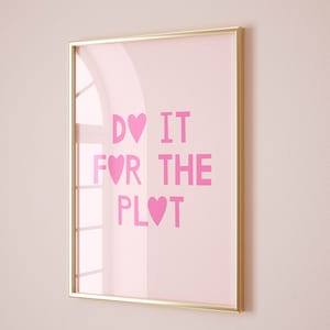 May include: A framed pink and gold print with the text "DO IT FOR THE PLOT" with hearts replacing the "O" in "DO" and the "O" in "PLOT".