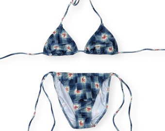 May include: A blue and white checkered bikini with pink floral accents. The top is a triangle style and the bottom is a cheeky cut.
