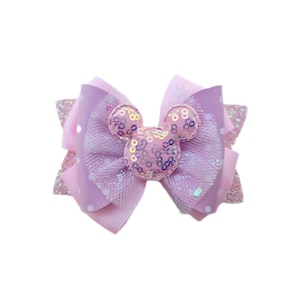 May include: A pastel-colored hair bow featuring a Mickey Mouse design. The bow is made of layered ribbons in shades of pink and lavender, with a polka dot pattern and glitter accents. The center features a sequined Mickey Mouse head.