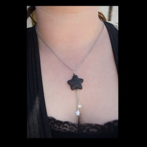 May include: A silver chain necklace with a black lava rock star pendant and two smaller silver star charms.