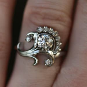 花のモチーフがヴィンテージ風のエンゲージリング、ラウンドカットのモアッサナイトダイヤモンドの結婚指輪、ホワイトゴールドのアールヌーボーリング、アンティークのエドワード朝風リング