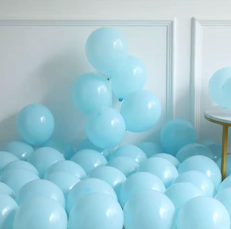 May include: A display of light blue balloons, some grouped and others spread out. The balloons are spherical and inflated, creating a celebratory feel. The background is a plain white wall. The balloons are suitable for a party.