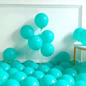 Peut inclure: Un groupe de ballons bleu turquoise dispos&eacute;s en grappe, certains ballons &eacute;tant li&eacute;s ensemble et d'autres &eacute;parpill&eacute;s sur le sol. Les ballons sont une d&eacute;coration de f&ecirc;te populaire.