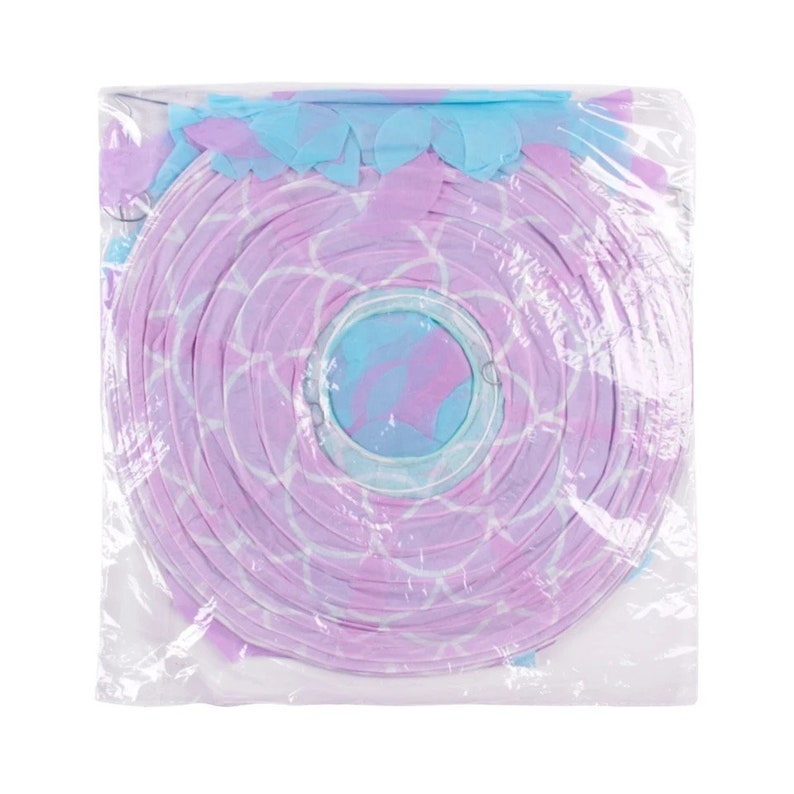 Op de afbeelding: Een roze en blauwe papieren lantaarn met een wit geometrisch patroon. De lantaarn is verpakt in een doorzichtige plastic zak.
