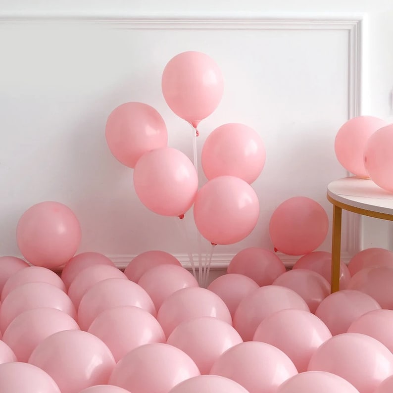 Peut inclure: Un grand groupe de ballons roses, certains attach&eacute;s et flottants, d'autres &eacute;parpill&eacute;s sur le sol.