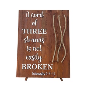 May include: A wooden sign with the text "A cord of THREE strands is not easily BROKEN" and the scripture reference "Ecclesiastes 4:9-12". Three strands of rope are attached to the sign.