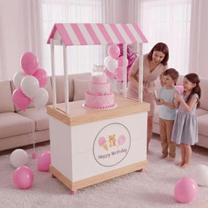 May include: A pink and white striped canopy over a white and wood-toned cart. A three-tiered pink cake with a "Happy Birthday" topper sits on the cart. Pink and white balloons and a woman and two children are also in the image.