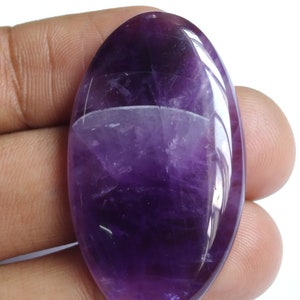 Puede incluir: Una gran piedra preciosa de amatista de forma ovalada, de color morado oscuro y superficie lisa y pulida.