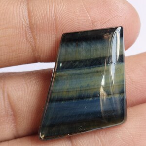 May include: A blue and gold tiger's eye gemstone cabochon with a faceted, irregular shape.
