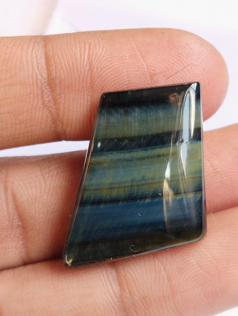 May include: A blue and gold tiger's eye gemstone cabochon with a faceted, irregular shape.