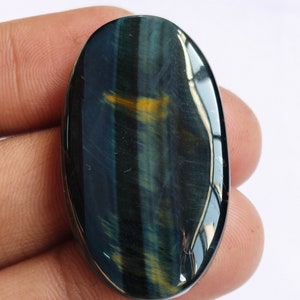 May include: A blue and gold tiger's eye cabochon, oval shaped, with a smooth, polished surface.