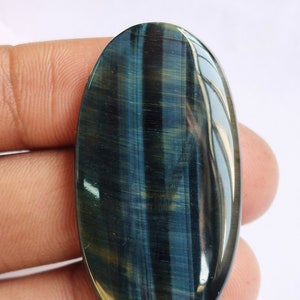 May include: A blue and green oval-shaped gemstone with a tiger's eye pattern. The gemstone is smooth and polished.