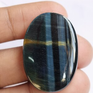 May include: A blue and gold oval-shaped gemstone with a tiger's eye effect.