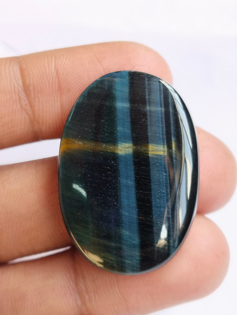 May include: A blue and gold oval-shaped gemstone with a tiger's eye effect.
