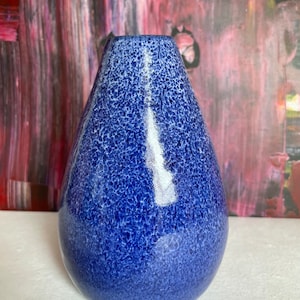 Könnte beinhalten: Eine blaue Keramikvase mit einem gesprenkelten Überzug. Die Vase hat eine abgerundete, tropfenförmige Form.