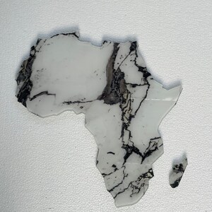May include: A white resin map of Africa with black and silver veins. The map is a decorative piece and is made of resin.