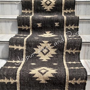 May include: A black and cream patterned rug with fringe on the edges. The rug is laid out on a set of stairs.