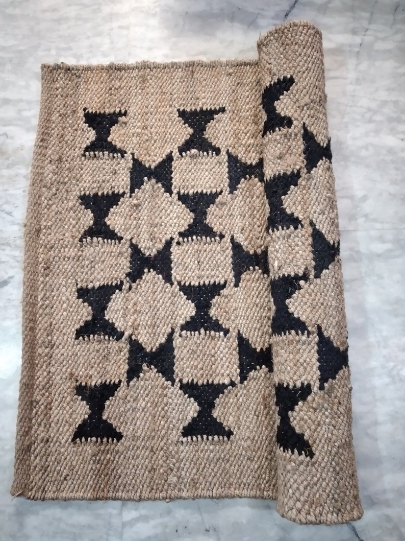 May include: A brown and black woven rug with a geometric pattern. The rug is rolled up on one side.