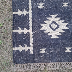 May include: A black and white geometric patterned rug with a fringe border. The rug has a dark blue background with white geometric shapes. The text "Jaipur Art and Rugs" is visible on the rug.