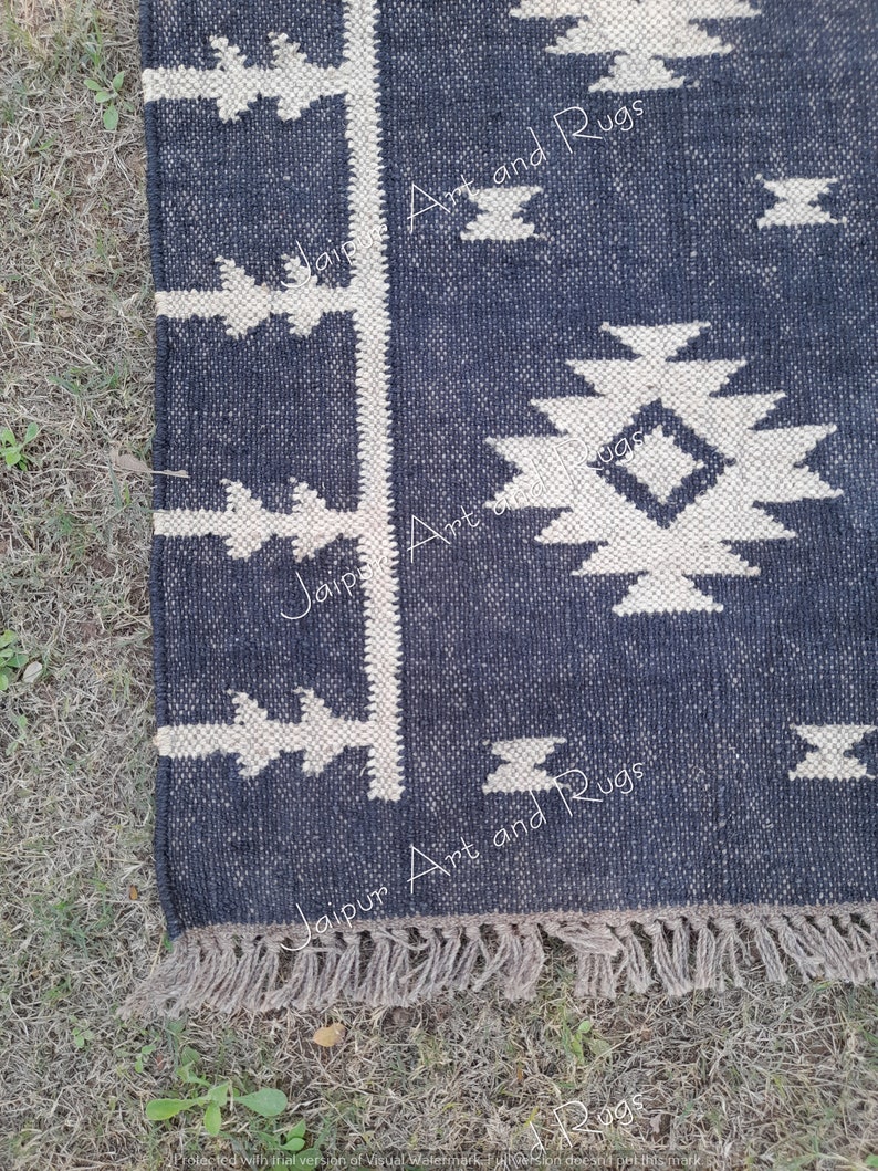 May include: A black and white geometric patterned rug with a fringe border. The rug has a dark blue background with white geometric shapes. The text "Jaipur Art and Rugs" is visible on the rug.