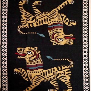 Puede incluir: Una alfombra negra con un borde blanco presenta dos tigres amarillos estilizados con rayas negras. Los tigres est&aacute;n mirando en direcciones opuestas y tienen un dise&ntilde;o geom&eacute;trico.