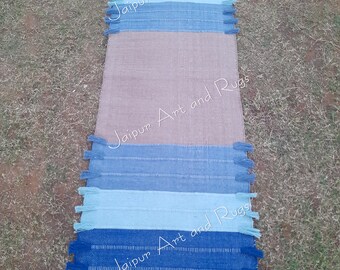 May include: A blue and beige striped rug with fringe on the ends. The rug has the text "Jaipur Art and Rugs" printed on it.