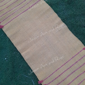 May include: A yellow and pink striped runner rug with tassels on the ends. The rug has the text "Jaipur Art and Rugs" printed on it.