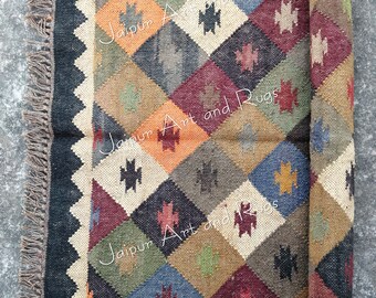 May include: A rolled-up, multi-colored rug with a geometric diamond pattern. The rug features a black border and fringe, with diamonds in shades of orange, blue, green, and burgundy. The text "Jaipur Art and Rugs" is visible on the rug.