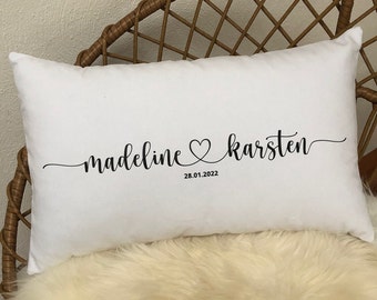 Könnte beinhalten: Weißes Kissen mit schwarzem kursivem Text, der "madeline karsten" mit einem Herzsymbol zwischen den Namen und dem Datum "28.01.2022" darunter lautet.
