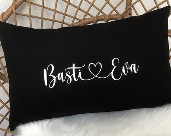 Könnte beinhalten: Schwarzes Kissen mit weißem Text, der in kursiver Schrift "Basti ♥ Eva" lautet.