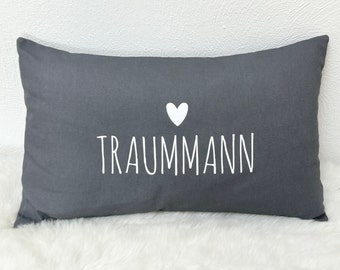 Könnte beinhalten: Grauer rechteckiger Kissenbezug mit weißem Text "TRAUMMANN" und einem weißen Herz über dem Text.
