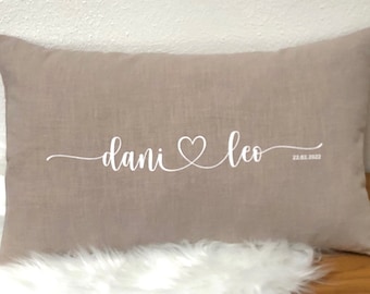 Könnte beinhalten: Ein beigefarbenes Leinenkissen mit weißer Stickerei, auf dem "dani ♥ leo 22.02.2023" steht.