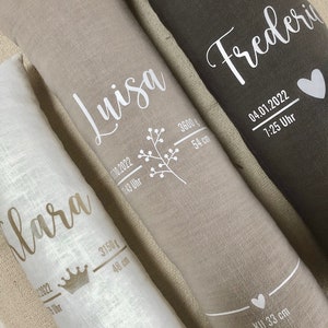 May include: Three long, rectangular pillows in white, beige, and dark grey. Each pillow features a name in a script font, alongside birth details including weight in grams, length in centimetres, and the time and date of birth.