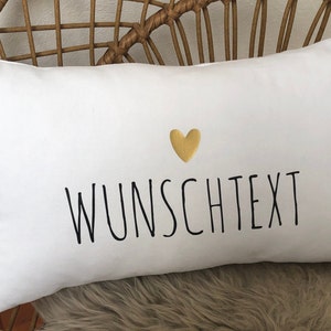 Könnte beinhalten: Ein weißes Kissen mit schwarzem Text, der "WUNSCHTEXT" lautet, und einem goldenen Herzen über dem Text.