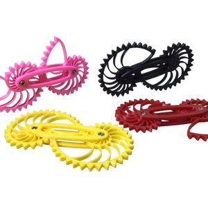 May include: Four interlocking gear-shaped toys in pink, yellow, black, and red. Each toy is made of plastic and has a unique design.
