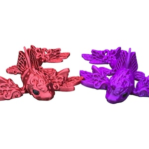 May include: Two decorative fish ornaments, one red and one purple, with intricate details and a whimsical design. The fish have wings and are made of a shiny material.