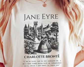 Pode incluir: Camiseta creme com o título "JANE EYRE" acima de uma ilustração em preto e branco de uma mulher com um vestido em frente a um castelo. O nome da autora, "CHARLOTTE BRONTË", e uma citação estão abaixo.