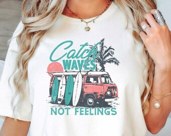 May include: White t-shirt with a graphic of a vintage van with surfboards and palm trees. The text "Catch Waves Not Feelings" is printed below the graphic.