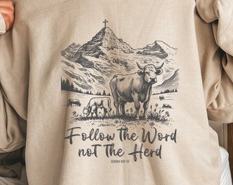 May include: A beige sweatshirt with a graphic print of a mountain range with a cross on top, two cows, and the text "Follow the Word not the Herd" with the scripture reference "Isaiah 55:8-13".