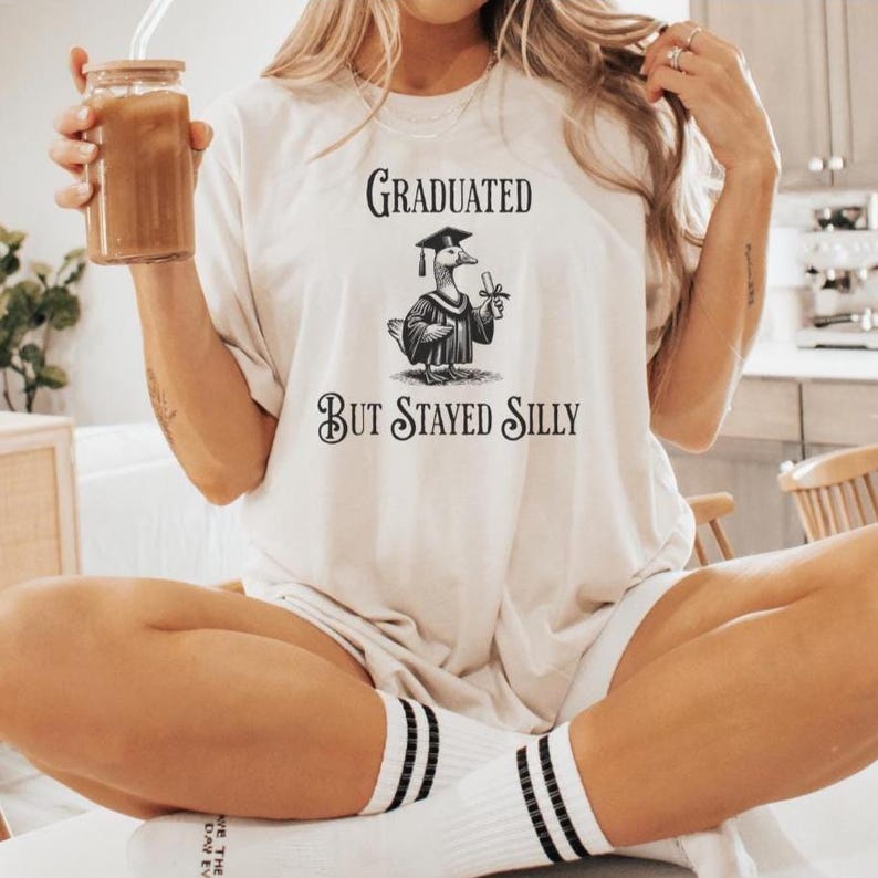 silly goose graduated! this graduation shirt has the silly goose holding a diploma wearing a cap and gown and says graduated but Stayed Silly and is a perfect funny grad gift. the silly and funny goose shirts are super trendy and this one is no exception