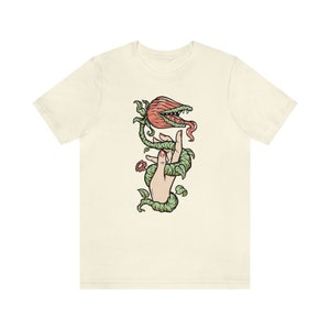 May include: A white t-shirt with a graphic of a hand holding a carnivorous plant with a red flower and green vines.