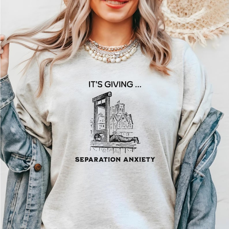 Medieval Dark Humor Shirt Featuring a whimsical depiction of a Medieval peasant lounging on a guillotine block, this shirt humorously declares, “It’s giving separation anxiety.” It offers a lighthearted take on realities of the past, making it an ideal choice for history buffs, Renaissance fair enthusiasts, and anyone who appreciates a laugh with a historical twist.