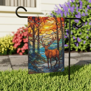 May include: A stained glass style garden flag featuring a deer standing in a forest with a sunset in the background.