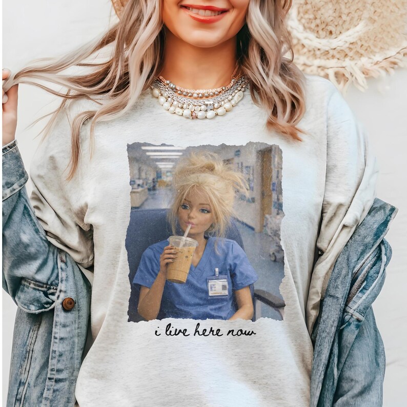 The Perfect Shirt for Nurses
The "I Live Here Now" nurse life shirt is a humorous ode to the demanding yet rewarding profession of nursing. Emblazoned with a comically frustrated doll sitting at a nurse's station clutching her essential iced coffee, this shirt captures the essence of long hours and dedication that nurses pour into their work. Ideal for new nurses, student nurses, or any medical professional, this funny nurse shirt makes for a thoughtful and amusing gift.