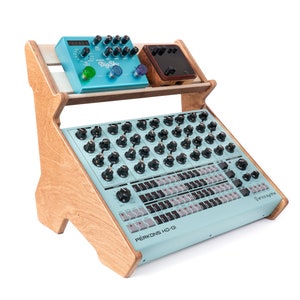 May include: A wooden stand with two shelves holds a blue synthesizer with black knobs and a blue pedal with the text "Big Sky" on it. The synthesizer is labeled "PERKONS HD-01" and "Erica Synths".