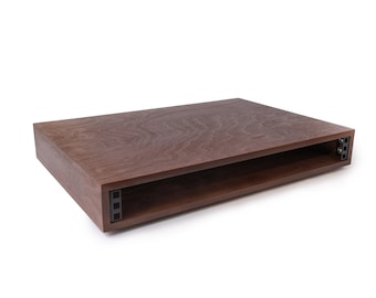 Könnte beinhalten: Ein rechteckiger Couchtisch aus dunkelbraunem Holz mit einem Regal darunter. Der Tisch hat eine glatte, polierte Oberfläche.